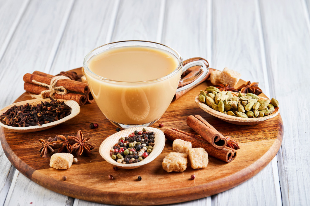 Traditional Indian drink - masala tea with spices. Cinnamon, cardamom, anise, sugar, cloves, pepper on a light wooden background.