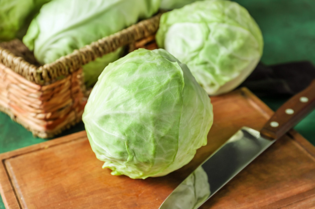 Fresh cabbage with knife on wooden board�