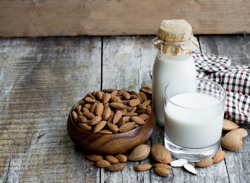 Almond milk in glass bottle on wooden table 