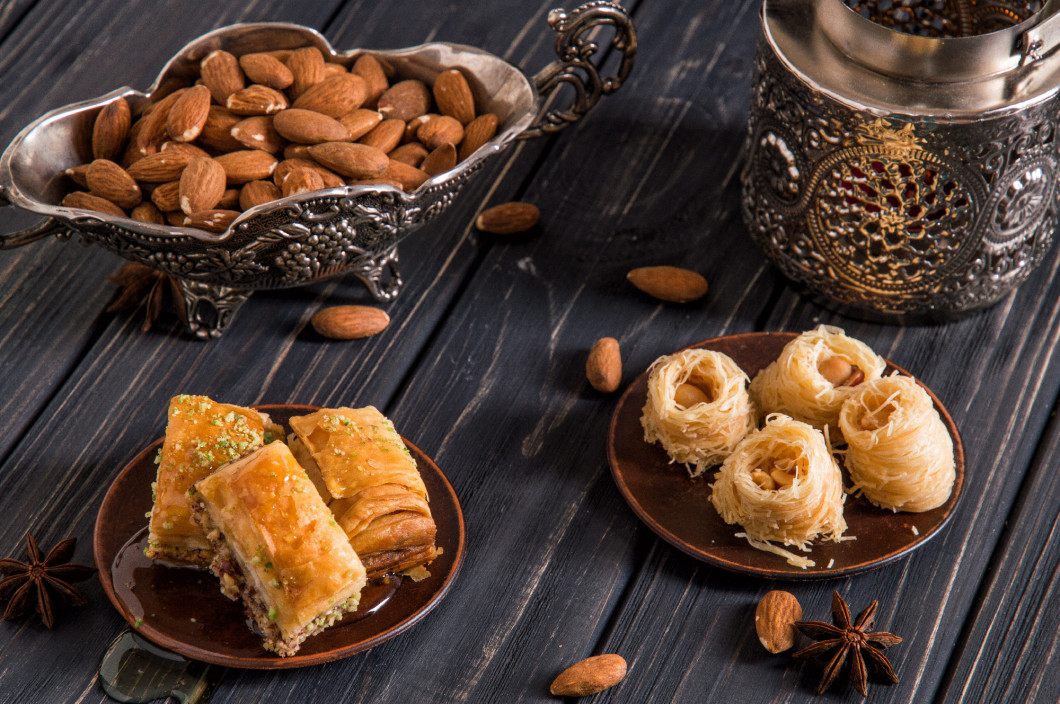 Close up. Eastern still life. Assortmant traditional homemade baklava. Turkish pottery and silverware. Dark wooden background.