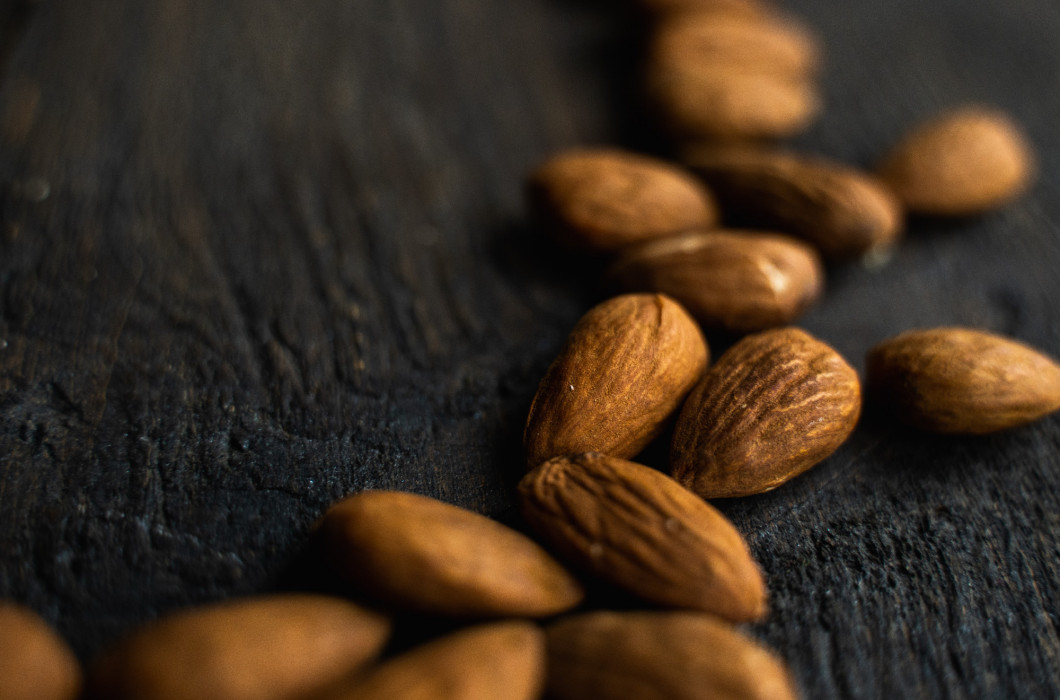 Almonds scattered on the wooden vintage table. Almond is a healthy vegetarian protein nutritious food. Almonds on rustic old wood.