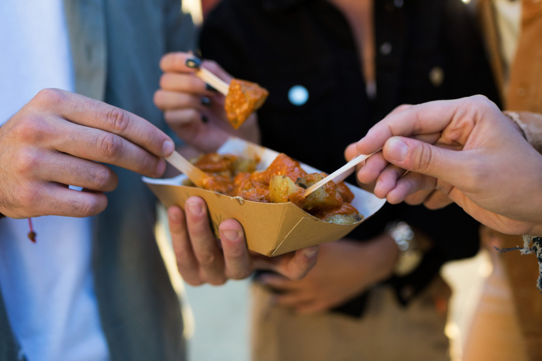 Group of friends visiting eat market and eating potatoes in the 