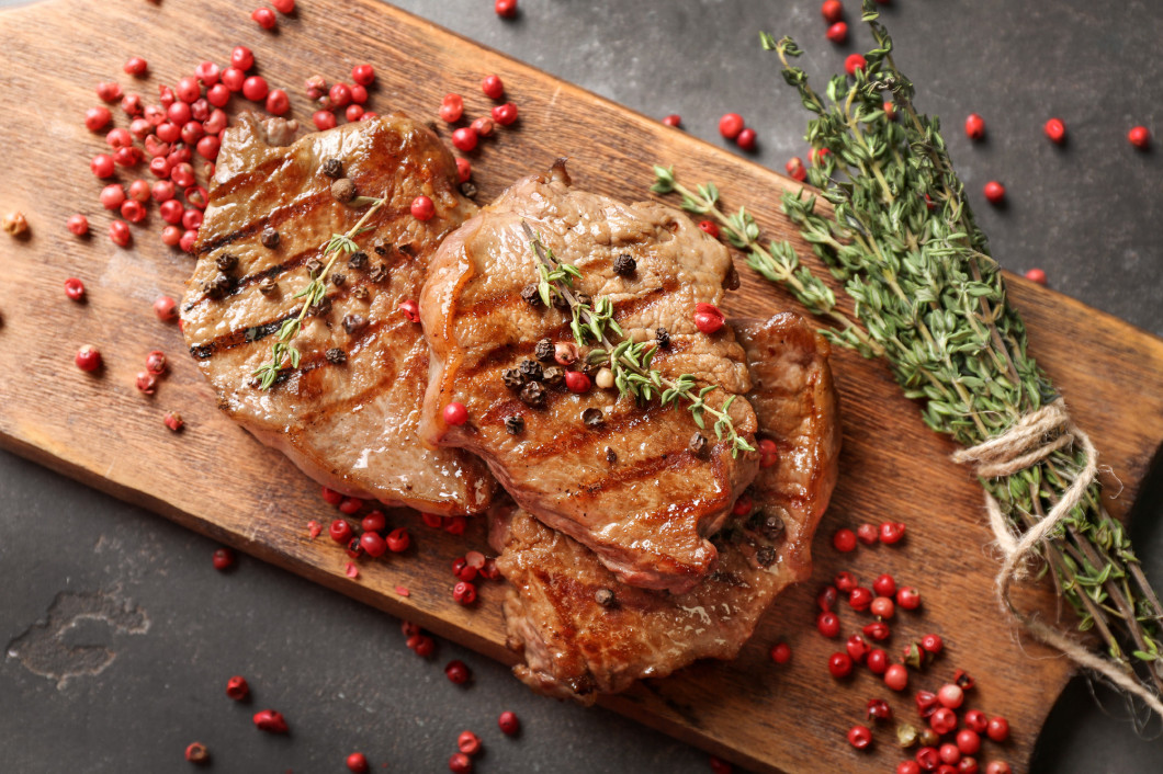 Delicious grilled steaks with spices on wooden board�
