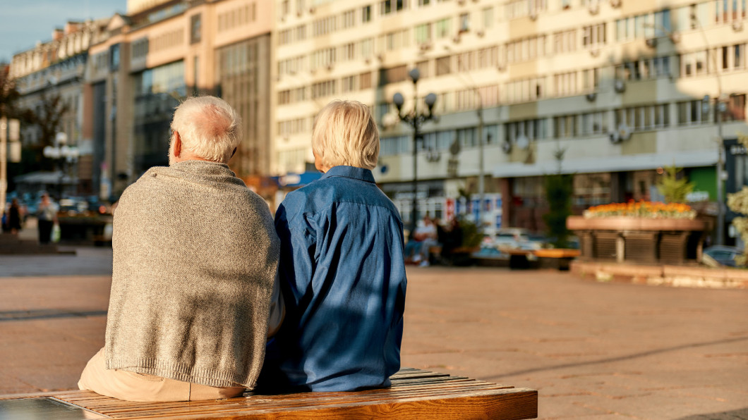 Resting. Back view of senior couple in casual clothes sitting on the bench together