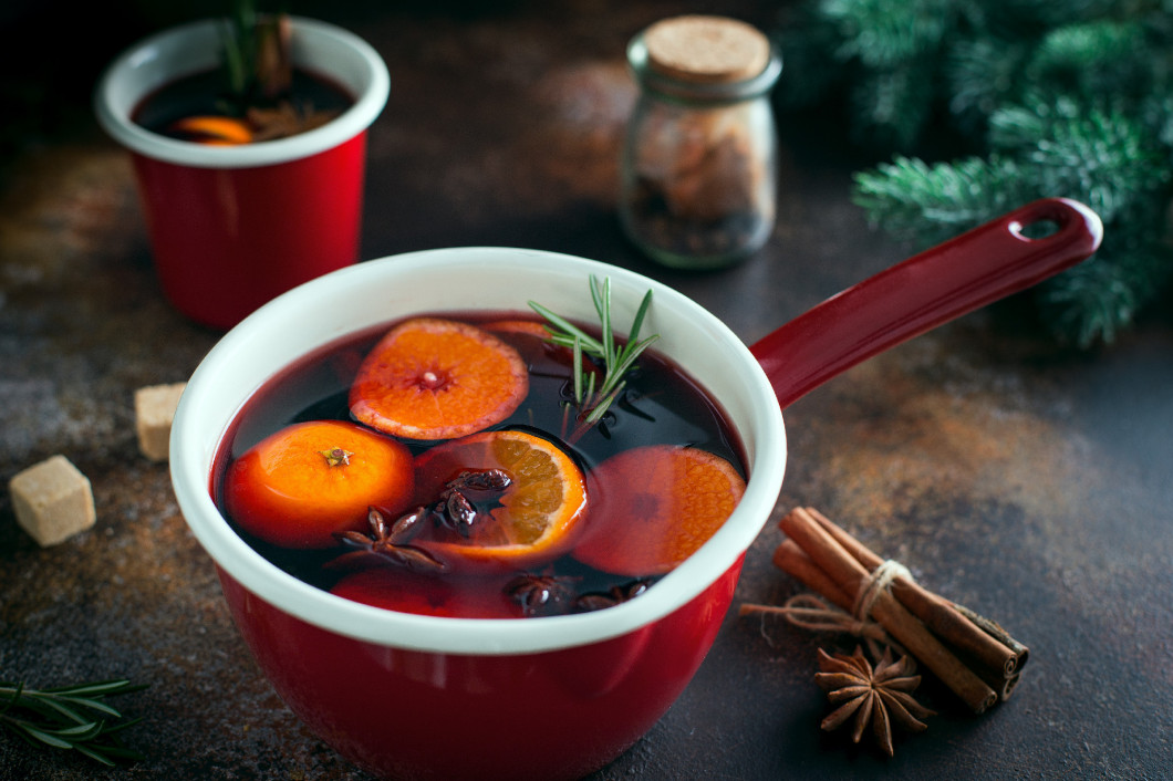 Spicy aromatic mulled wine with tangerine and spices in an enamel ladle, horizontal