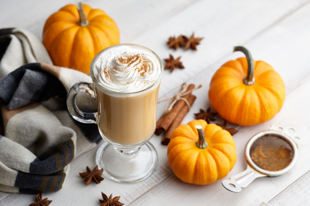 Fall pumpkin spice latte with whipped cream on white wooden back