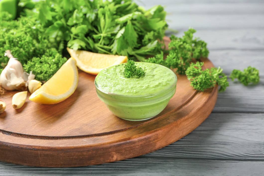 Delicious yogurt sauce in bowl with ingredients on wooden background�