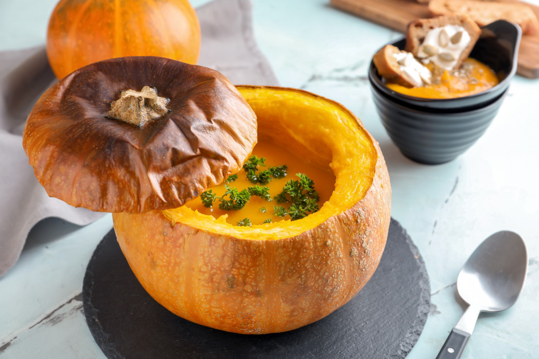 Tasty cream soup served in pumpkin on light table�
