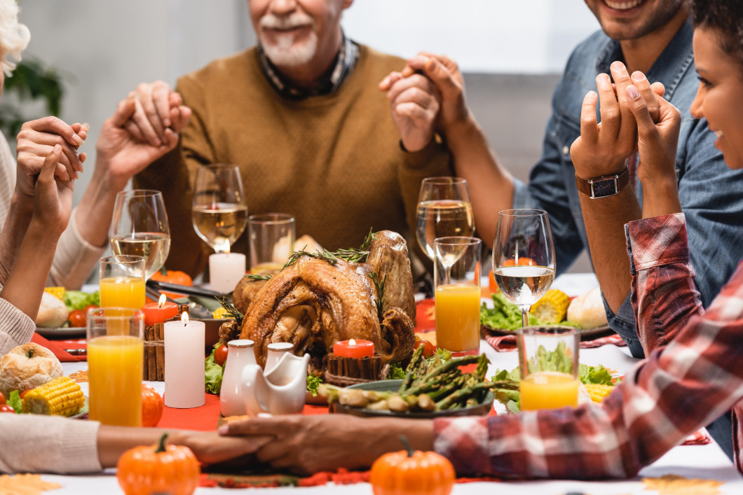 cropped view of pleased multiethnic family holding hands on thanksgiving