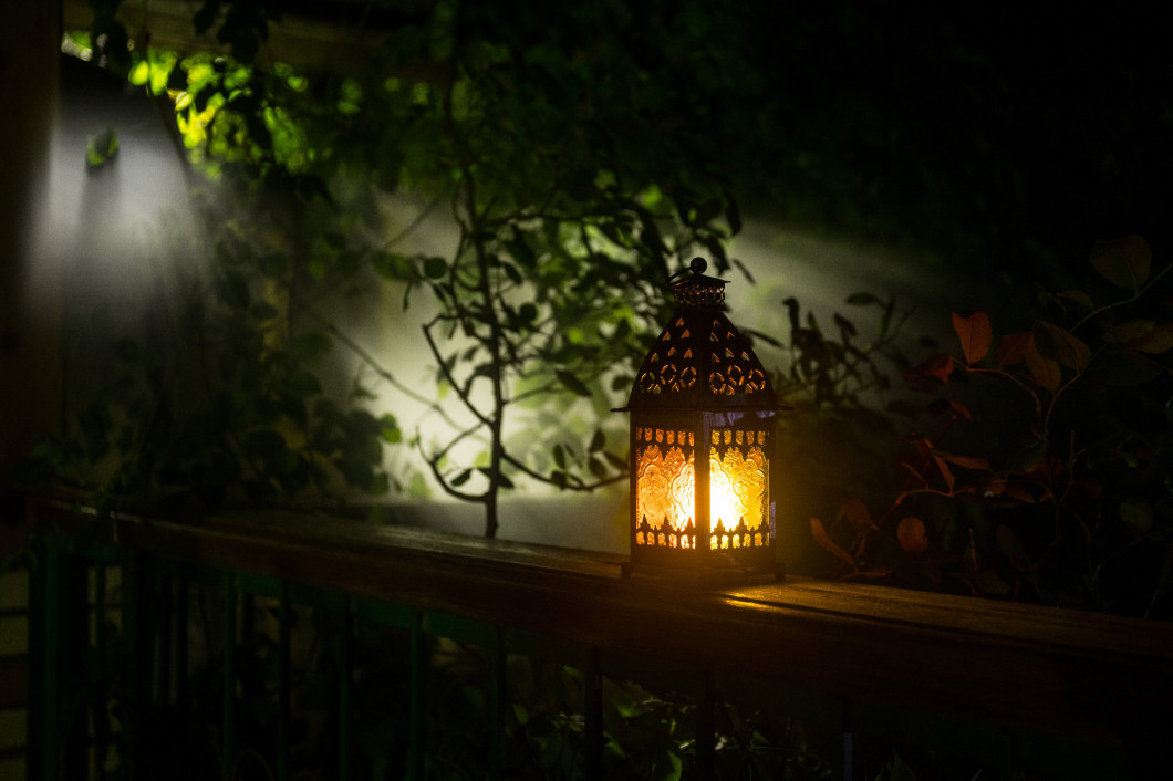 Retro style lantern at night. Beautiful colorful illuminated lamp at the balcony in the garden. Selective focus