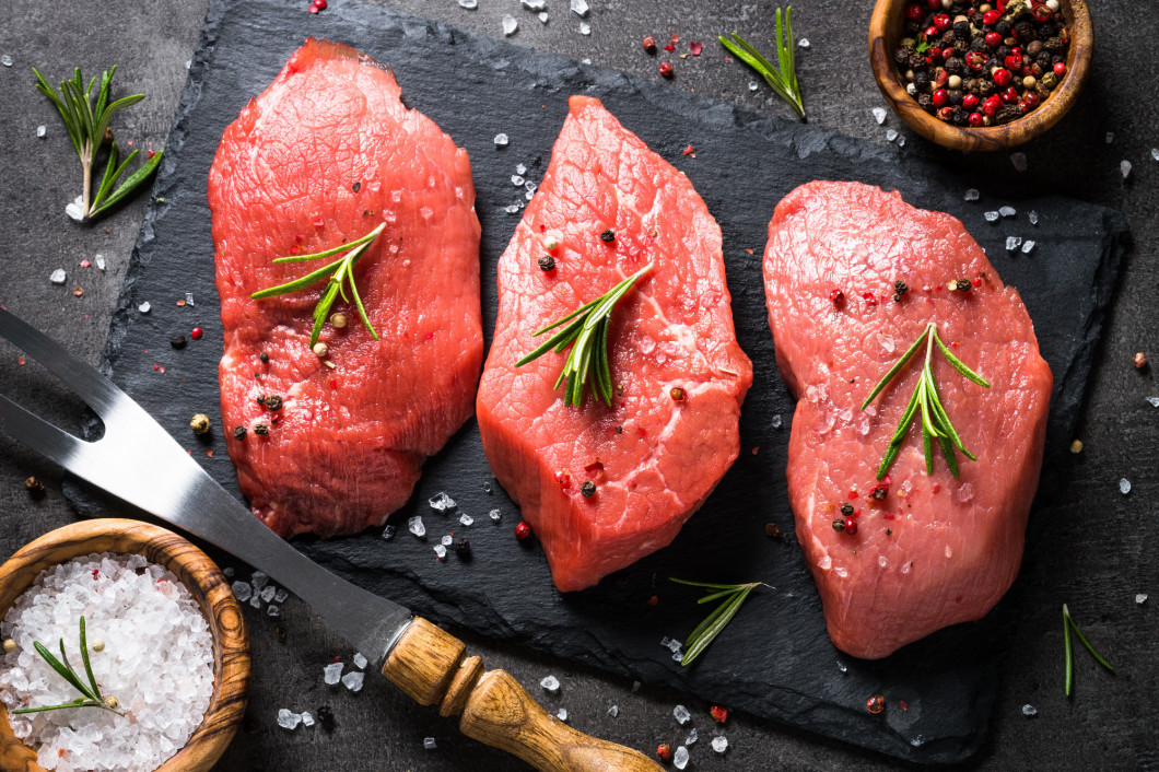 Beef steak with rosemary and spices on black background