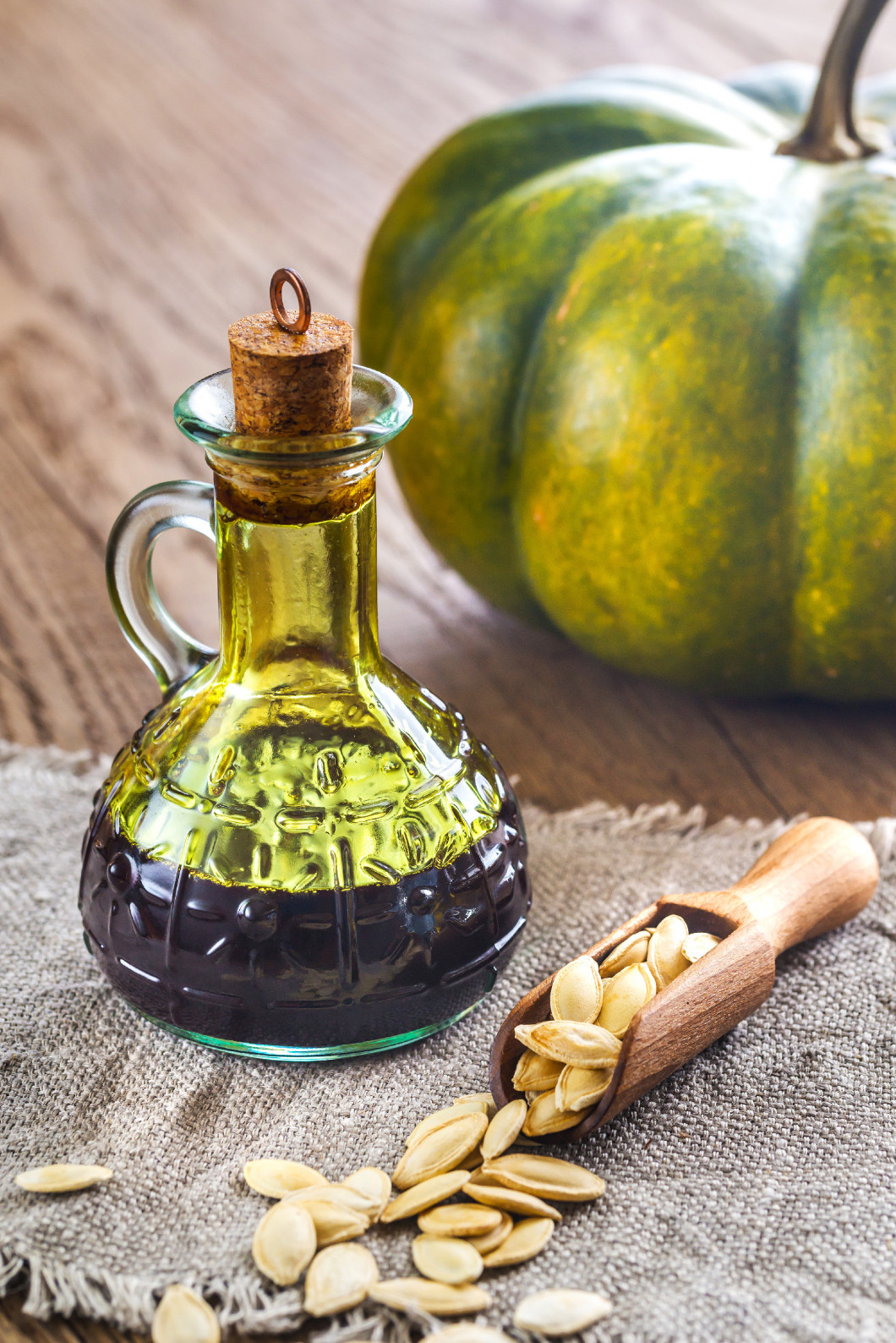 Bottle with pumpkin oil on the wooden background