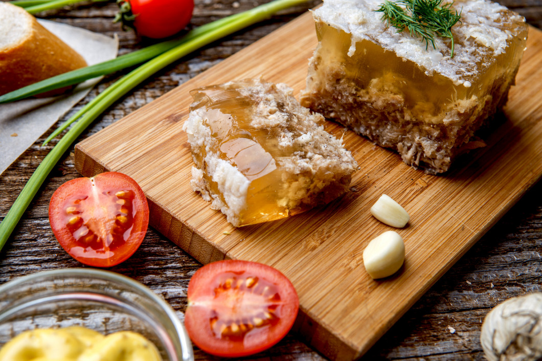 Homemade jelly meat with mustard, bread, tomatoes and garlic on 