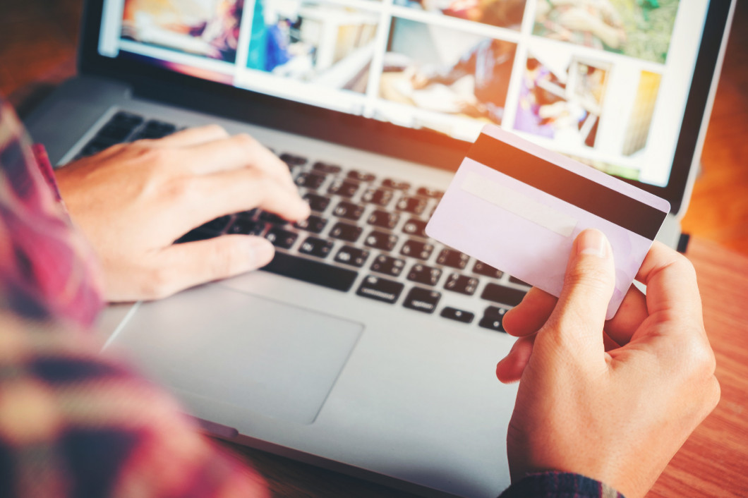 Man's hands typing laptop keyboard and holding credit card onlin