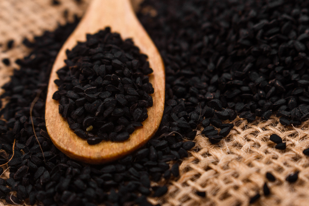 grains of black cumin and oil on the rustic background