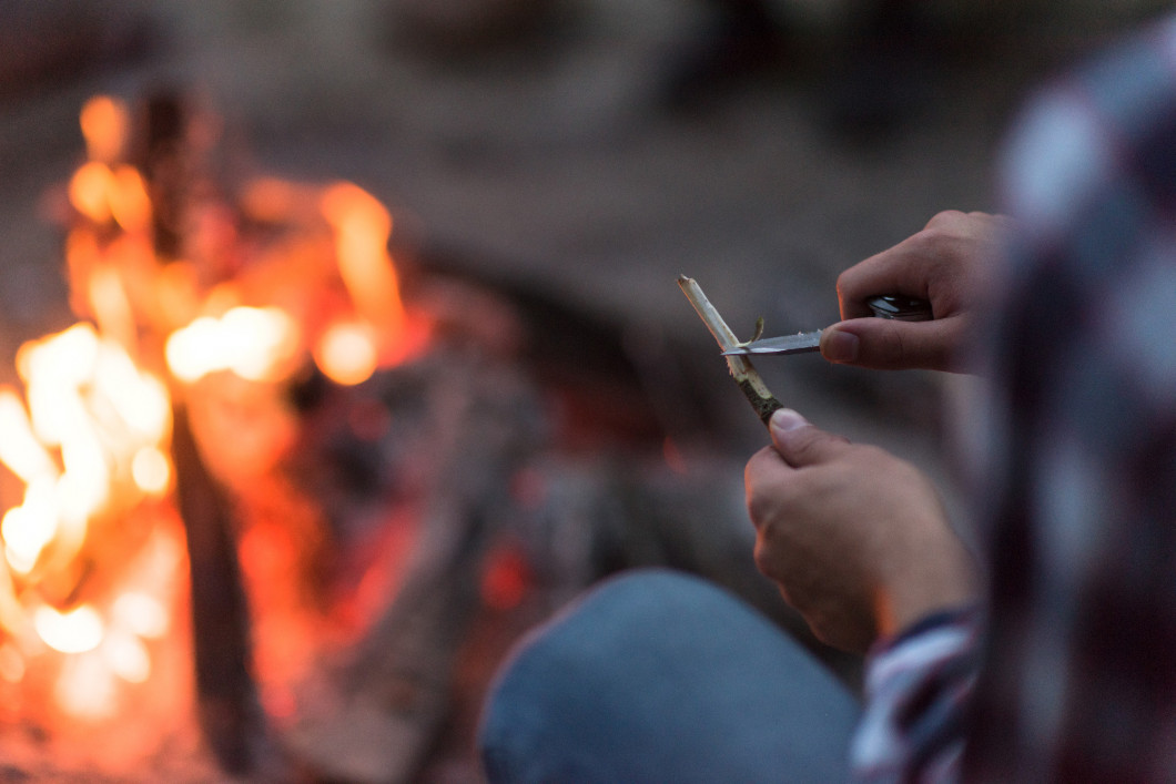 young friends relaxing around campfire