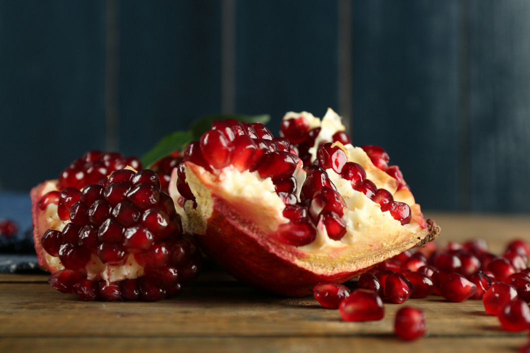 Pomegranate seeds on wooden table, closeup