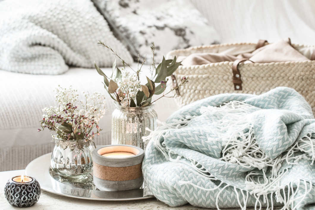 Home decorations in the interior. A turquoise blanket and wicker basket with a vase of flowers and candles