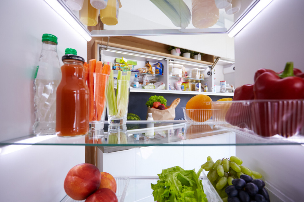 Portrait of female standing near open fridge full of healthy food, vegetables and fruits. Portrait of female