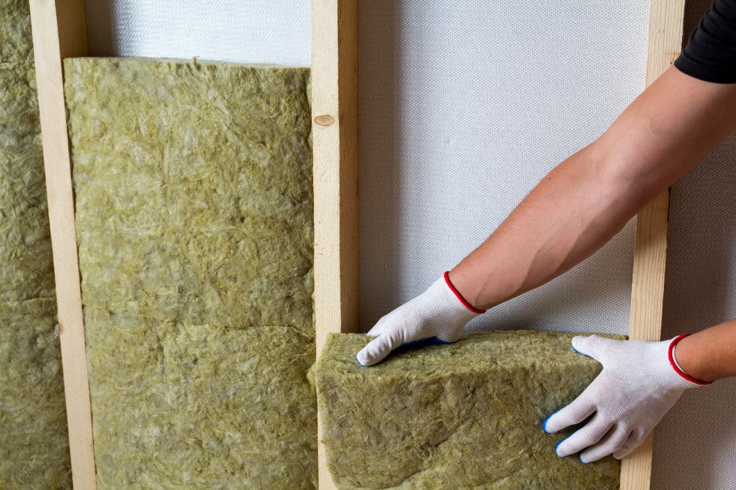 Close-up of worker hands in white gloves insulating rock wool in