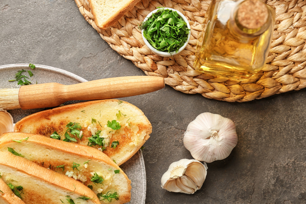 Plate with delicious homemade garlic bread on table�