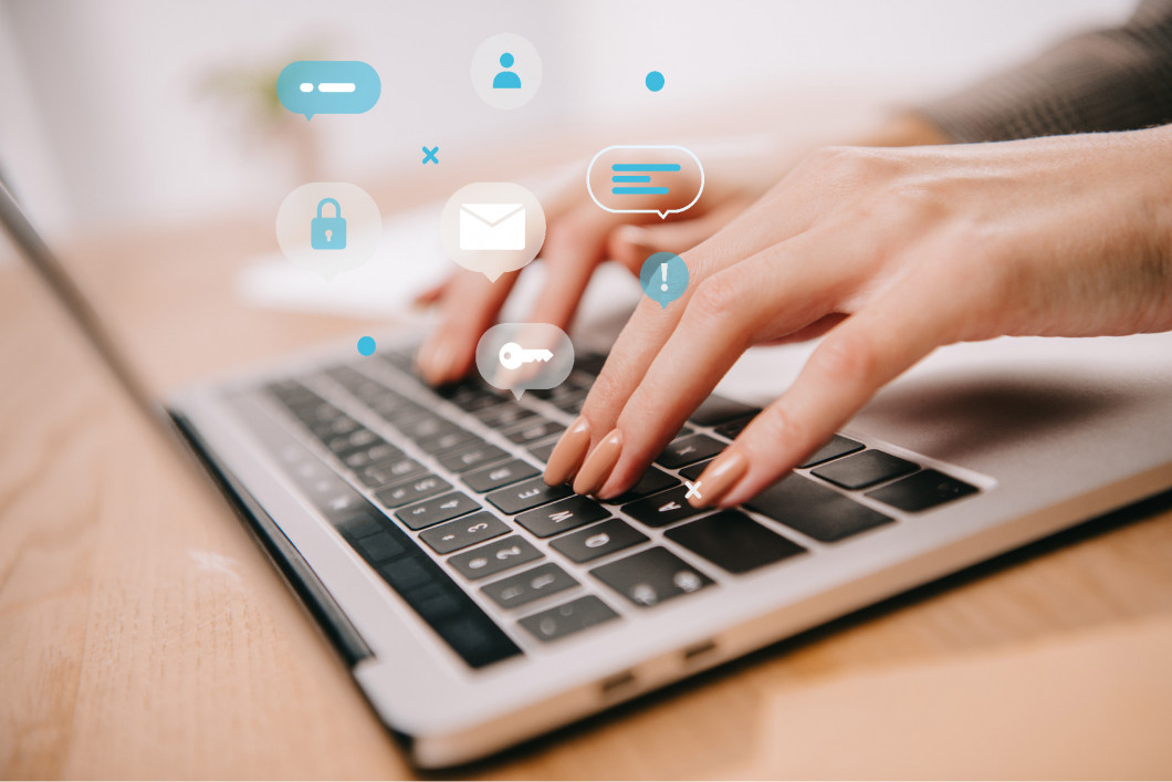 close up view of woman typing on laptop at wooden table with email marketing icons