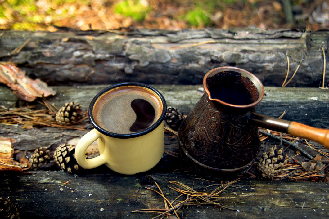 Yellow metal  cup with hot coffee and cezve on the wooden backgr