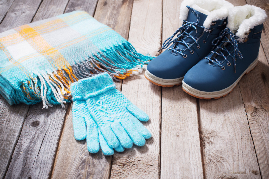 Winter shoes, gloves, scarves  on old wooden background