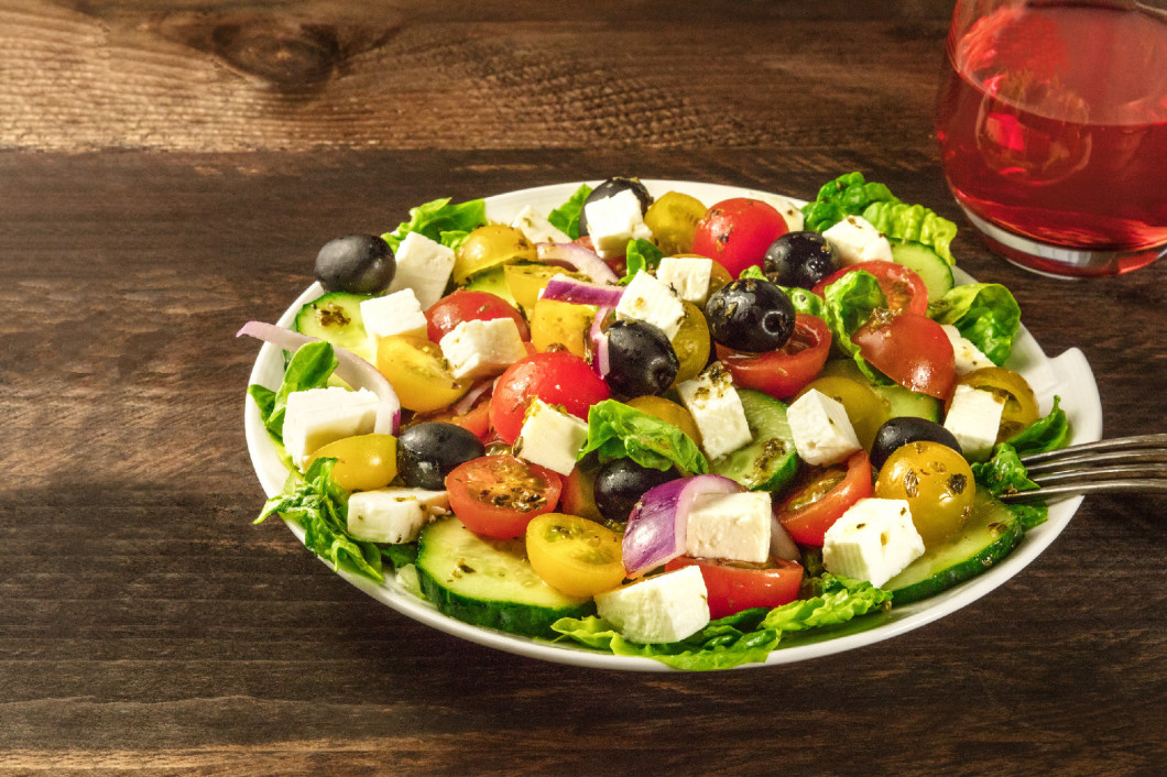 Greek salad with feta, fresh vegetables, and rose wine