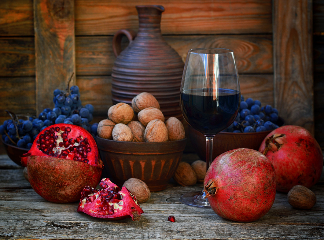 pomegranate, walnuts and glass of wine on a wooden background