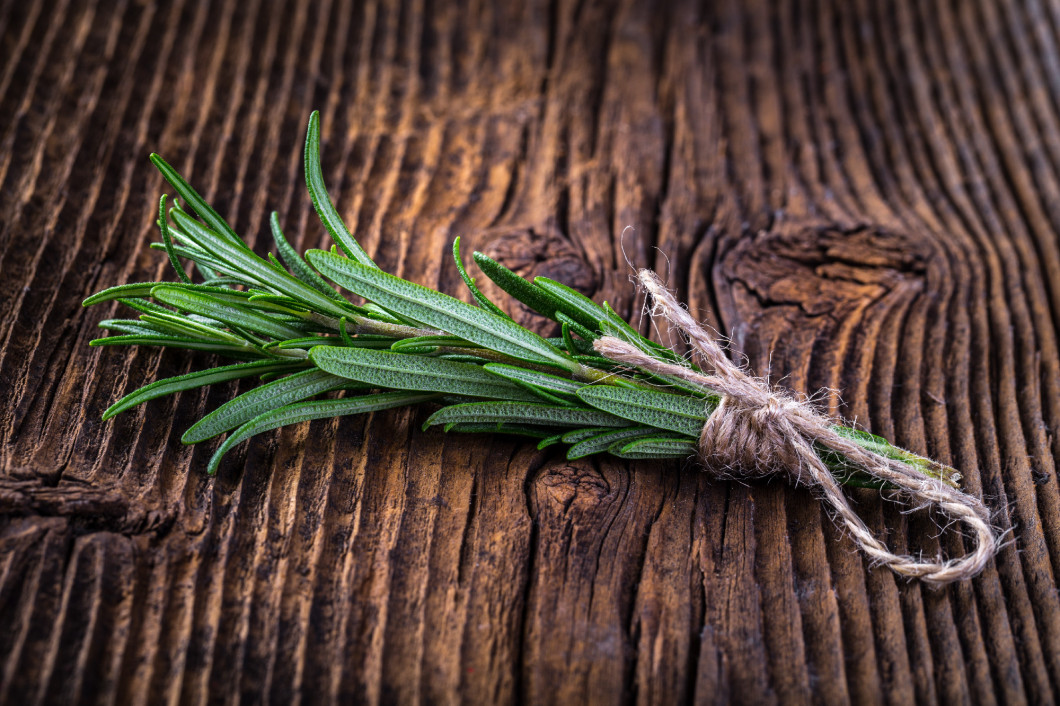 Fresh fragrant rosemary branch on vintage wooden table