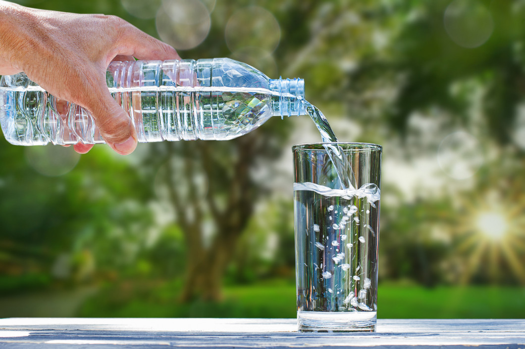 Man's hand holding drinking bottle water and pouring water into 