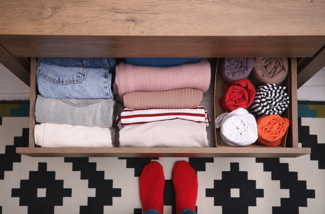 Woman near open drawer with folded clothes indoors, top view. Ve