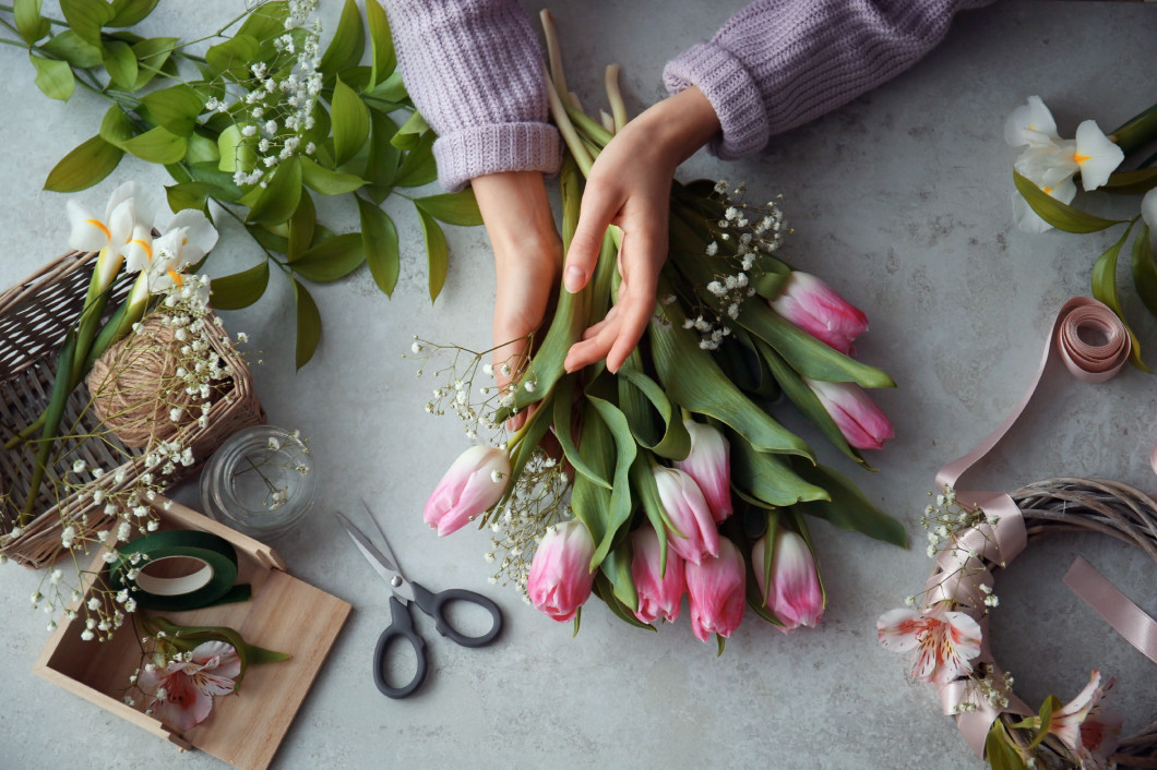 Female decorator creating beautiful bouquet at table�