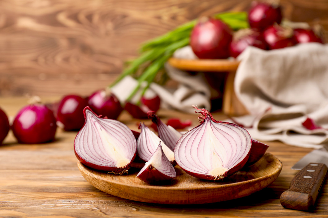 Plate with pieces of fresh raw onion on wooden background