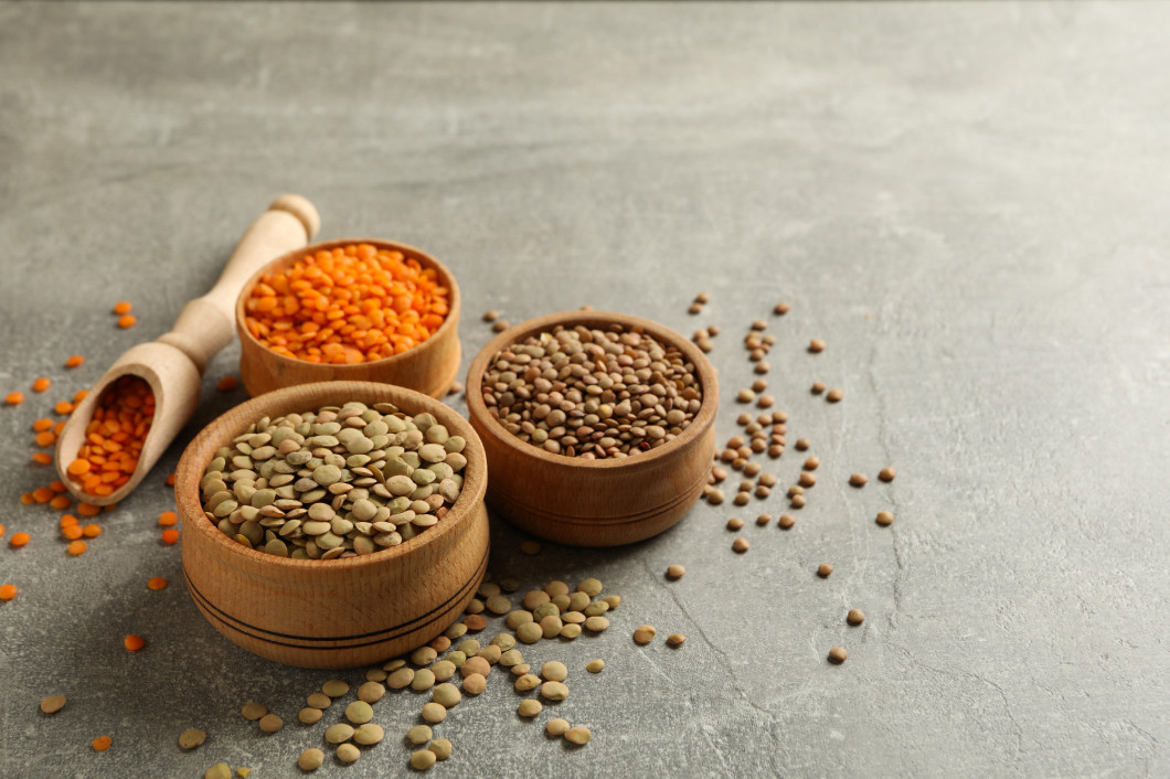 Scoop and bowls with different legumes on gray background