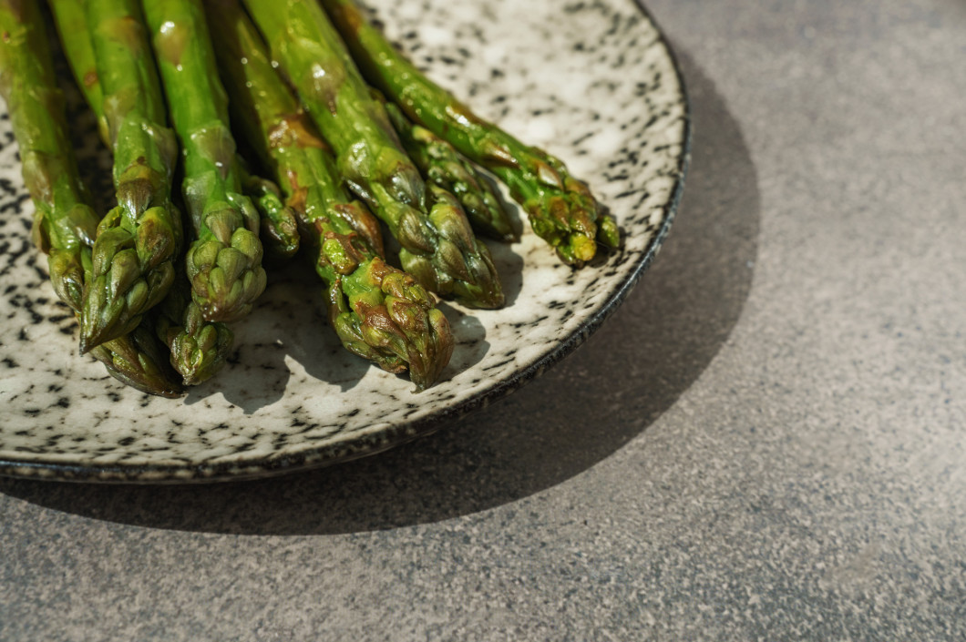 Fresh green asparagus. Cooking healthy food on a beautiful colorful handmade plate. Bunches of green asparagus, top view. Image. Copy space