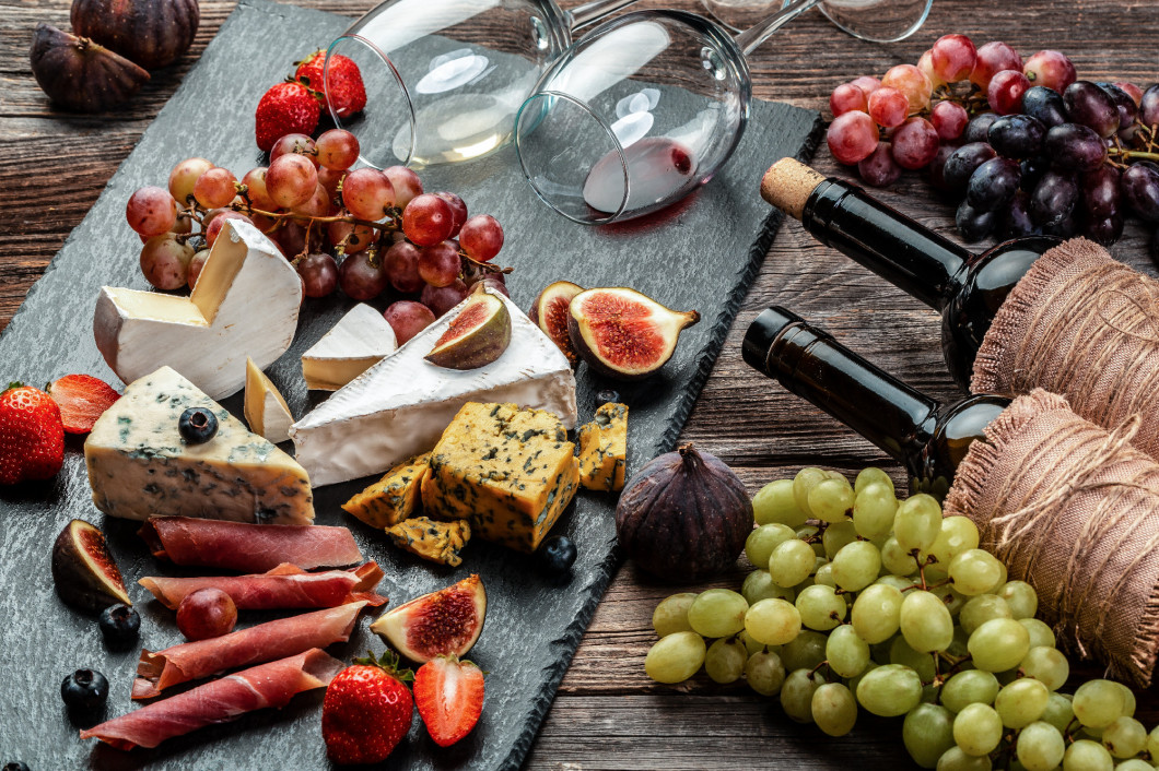 Various kind of cheese, traditional pieces of french, italy and spanish manchego cheese with grapes and figs served on wooden table