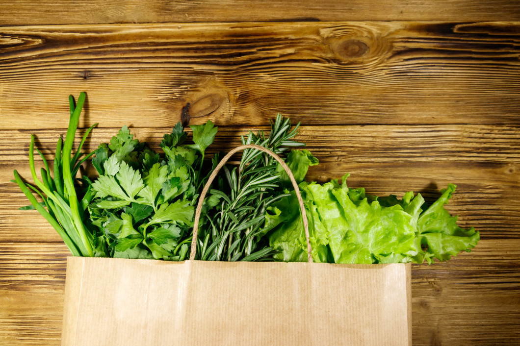 Paper bag with green onion, rosemary, lettuce leaves and parsley