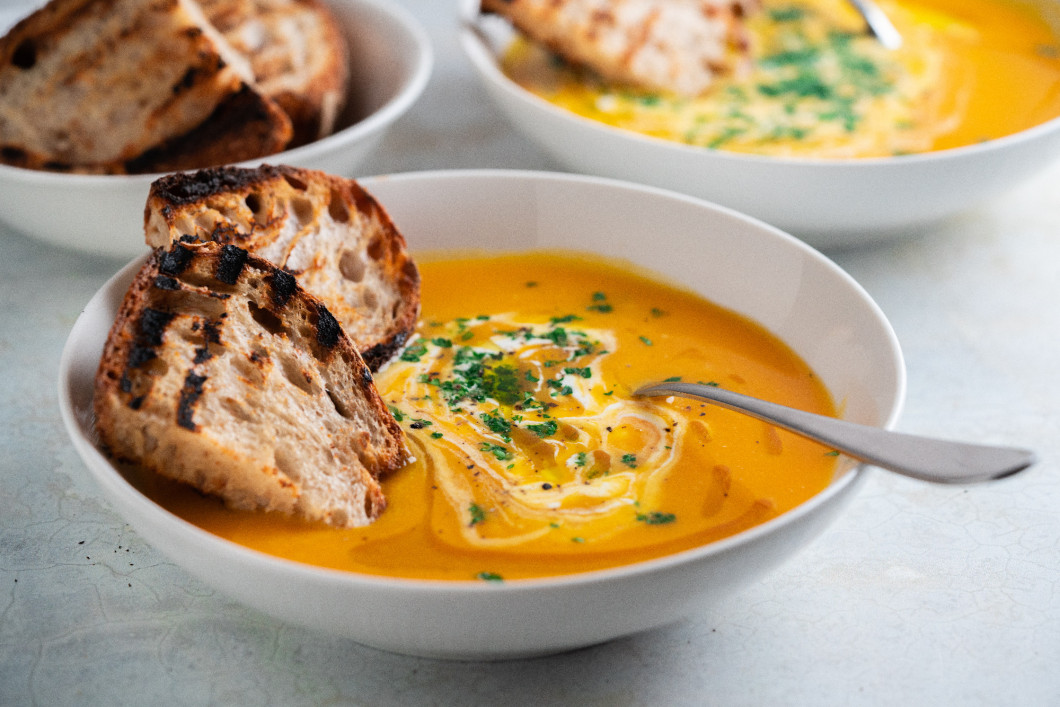 Pumpkin soup served in a bowl with croutons, parsley and olive oil.