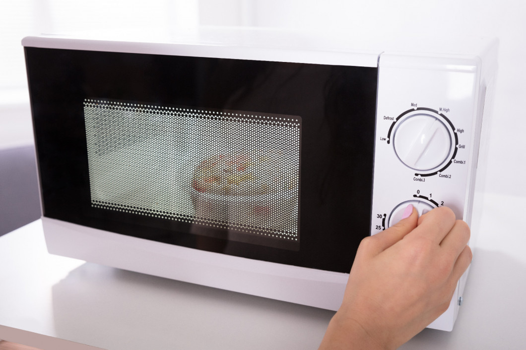 Woman Using Microwave Oven For Preparing Food