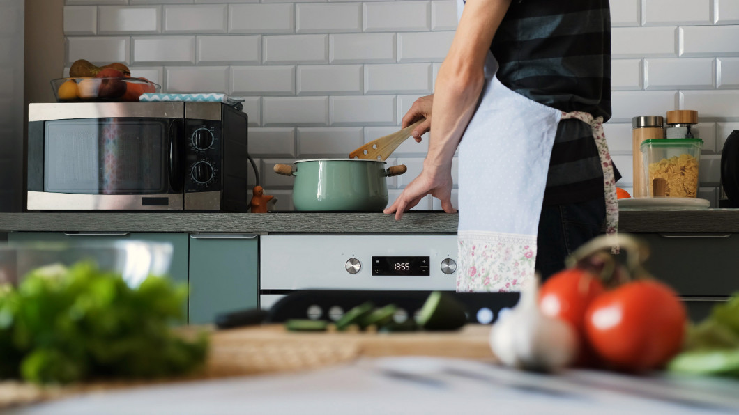 Man in apron cooking soup at home