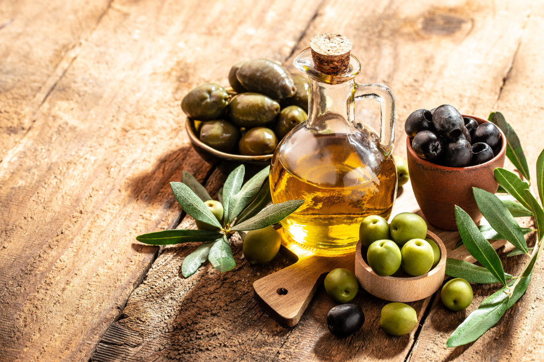 green olives with olive oil. extra virgin olive oil jars on a wooden background. place for text