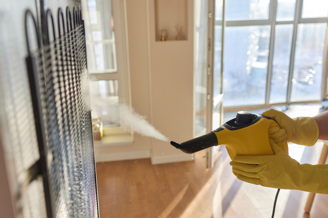 girl wipes the refrigerator with a rag from dirt, dust and grease. a girl does cleaning in rubber gloves in the kitchen by the fridge. cleaning with a steam generator.