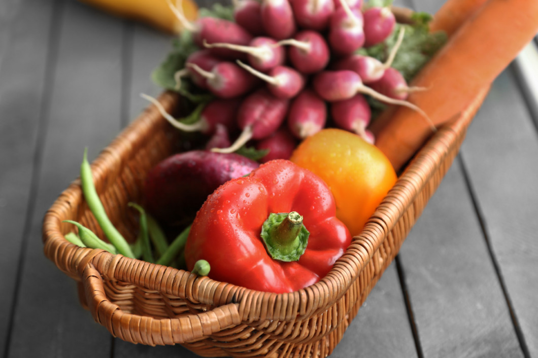 Fresh vegetables in wicker basket on table, closeup