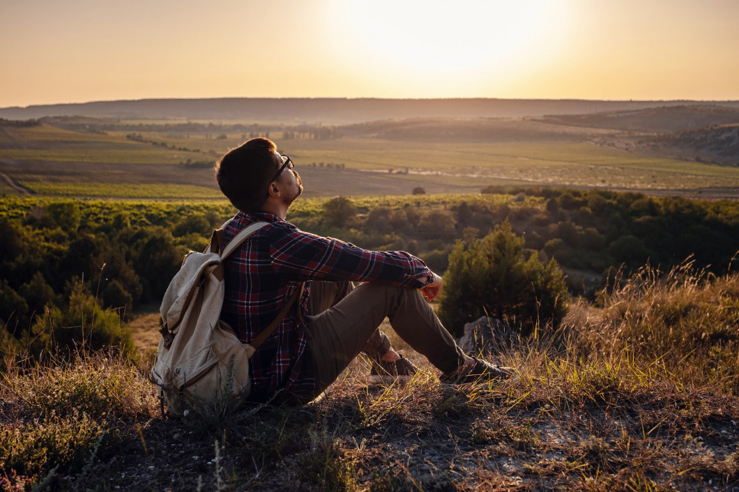 Hiker with backpack sitting on top of the mountain