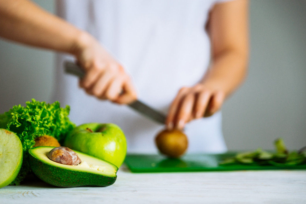 green fruits on front. woman cut fruits on background. healthy f