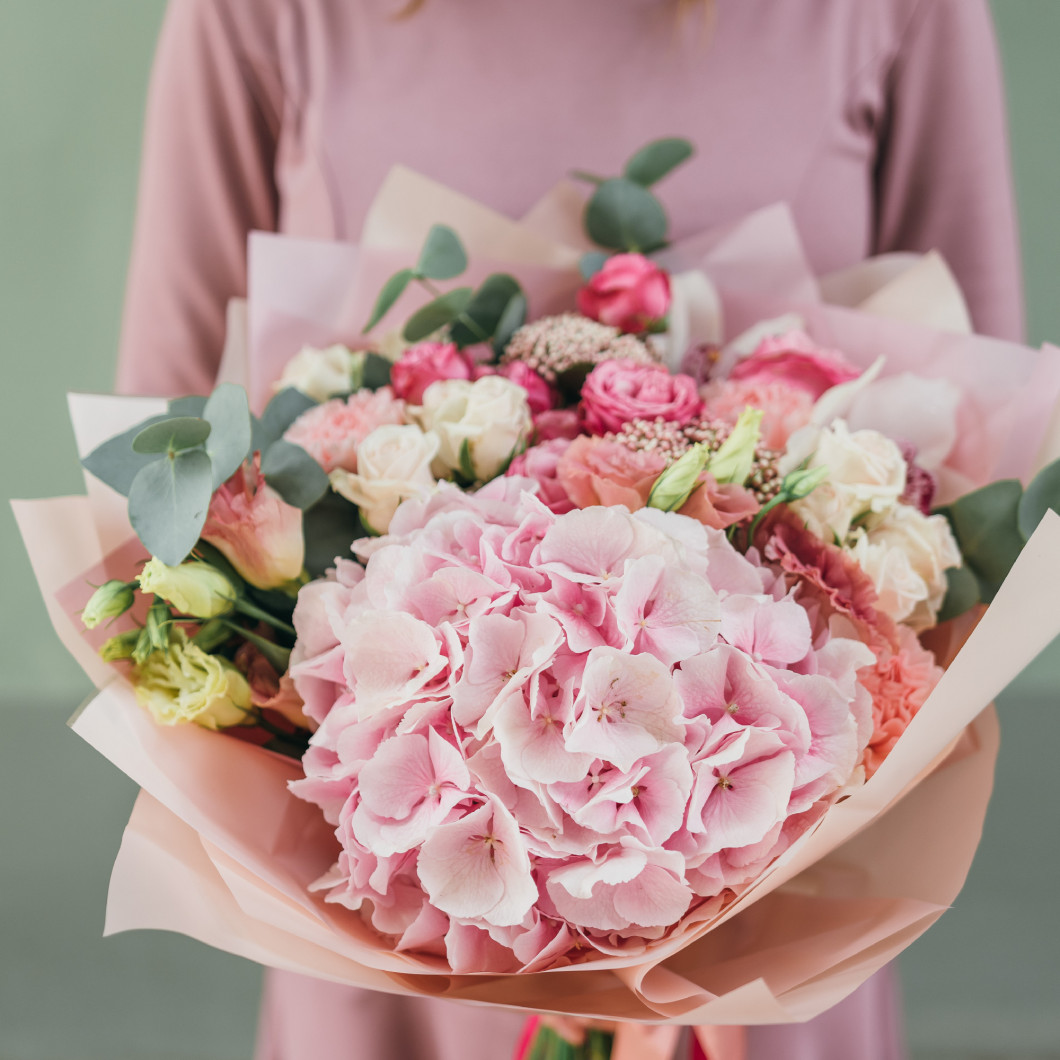 Colorful bouquet of different fresh flowers in the hands of florist woman. Rustic flower background. Craft bouquet of flowers.