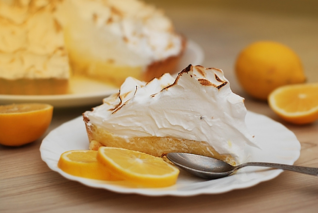 A piece of Lemon Tart with Meringue Caramelized Cream on plate on white wooden background